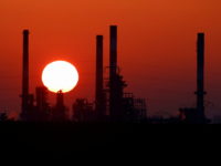 The sun sets behind the chimneys of the Total Grandpuits oil refinery, southeast of Paris, France, March 1, 2021.  REUTERS/Christian Hartmann